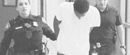 Man in handcuff being escorted by two prison staff