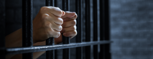 Hands gripped bars of a cell