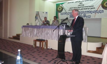 An image of Professor Andrew Coyle standing at a lectern